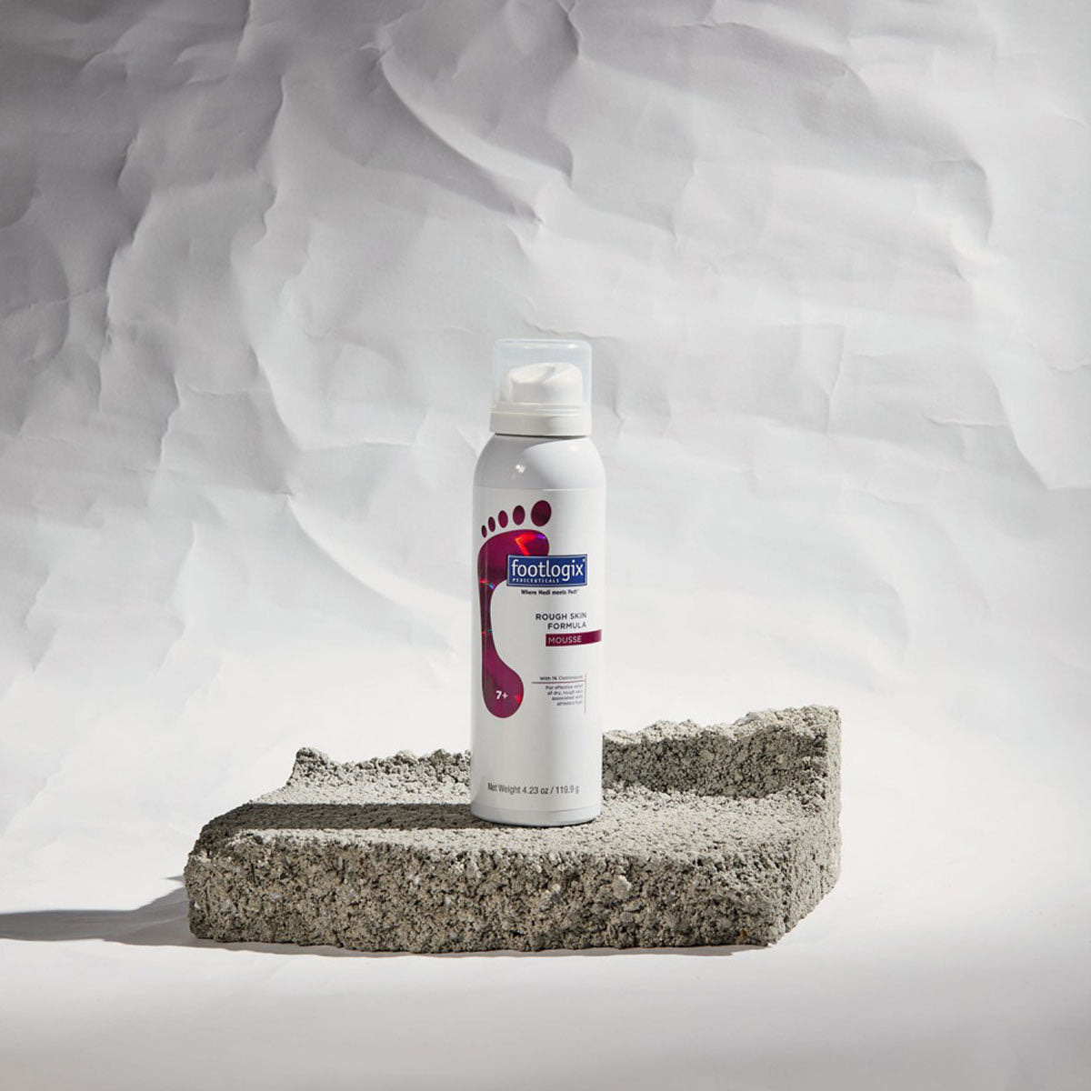 Footlogix Rough Skin Formula productfoto op een achtergrond met ruwe huidstructuur voor de behandeling van eelt en schilferige voeten.